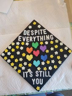 a decorated graduation cap that says despite everything it's still you on the table