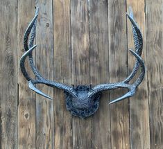 a deer's head mounted on the side of a wooden wall with antlers