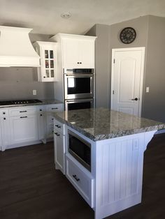 a kitchen with white cabinets and an island in front of the stove, oven and microwave