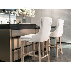 two white bar stools sitting in front of a counter top with flowers on it