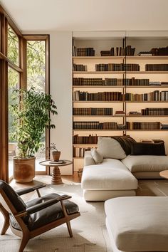 a living room filled with furniture and bookshelves next to a large open window