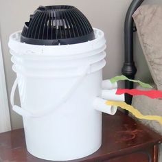 a large white bucket sitting on top of a wooden table next to a wall mounted heater