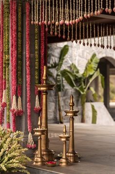 three brass candlesticks with beads hanging from the ceiling in front of a building