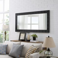 a living room filled with furniture and a large mirror on the wall above it's headboard