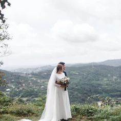 a bride and groom standing on top of a hill