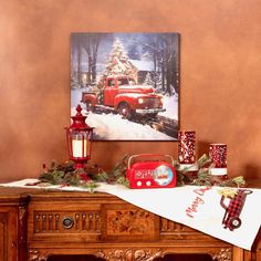 an old fashioned red truck with a christmas tree on it is displayed in front of a painting