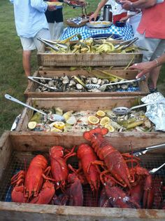 lobsters and corn on the cob are being served at an outdoor barbecue event