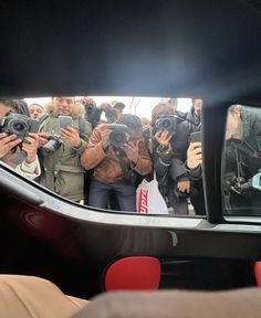 a group of people taking pictures in a car mirror