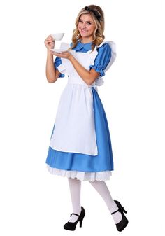 a woman dressed in a blue and white dress holding a teacup while posing for the camera