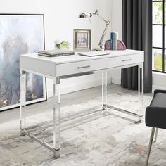 a white desk sitting in front of a window next to a chair and framed pictures