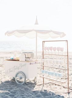 an ice cream cart is set up on the beach with cups and plates in it