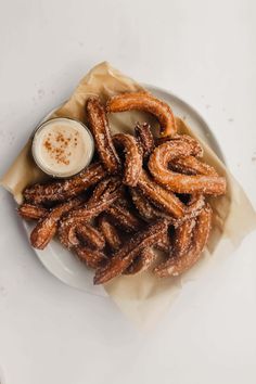 a white plate topped with churros next to a bowl of dip