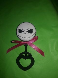 a bottle opener with a jack skellingy face on it's side and a pink ribbon around the mouth