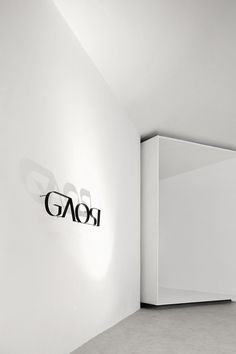 an empty room with a white wall and black logo on the wall next to it