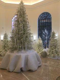 there is a fake christmas tree in the middle of this room with snow on the ground