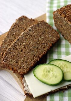 two slices of bread with cucumbers on a cutting board next to each other