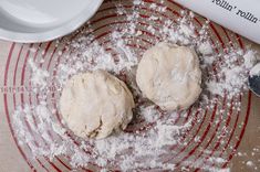 two doughnuts sitting on top of a red and white plate with powdered sugar