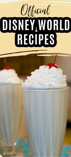 two glasses filled with whipped cream and topped with cherries, on top of a table