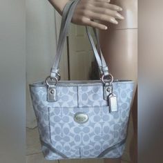 This Is Such A Dynamite Color. Its Elegant And Classy, Very Dressy Too. Its A Greyish Silver With Very Very Light Greyish Monogram. Nothing At All To Speak Off In Flaws. Silver Hardware In Details. The Inside Is A Very Soft Grey Color And It Has Three Pockets, One With A Zipper. The Bag Closes With A Zipper At The Top. Appr . 13 X 10 X 3 Classic Silver Shoulder Bag With Removable Pouch, Classic Silver Tote Shoulder Bag, Classic Silver Bag For Everyday Use, Classic Silver Bag For Daily Use, Classic Silver Shoulder Bag For Daily Use, Designer Silver Shoulder Bag With Handles, Classic Silver Shoulder Bag With Handles, Classic Coach Silver Bag, Classic Silver Coach Shoulder Bag