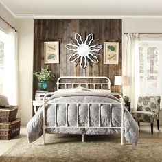 a white bed sitting in a bedroom next to a wooden paneled wall with pictures on it