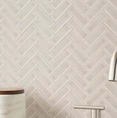 a bathroom with white tiles on the wall and a wooden sink faucet next to it