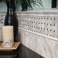 a candle sitting on top of a table next to a vase with a plant in it