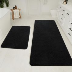 two black bath mats in a white bathroom