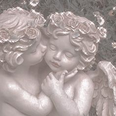 two little angels are touching each other with their hands and eyes closed in front of some flowers