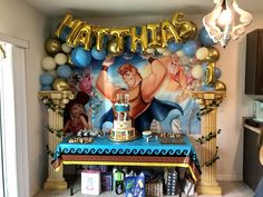 a birthday cake on a table in front of a wall with the name's characters