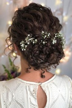 the back of a woman's head with flowers in her hair and pearls on it