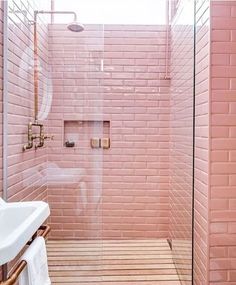 a bathroom with pink brick walls and wooden flooring is shown in this image, the shower stall has glass doors on both sides