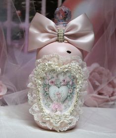 a pink bottle with a heart in the middle and a bow on top is sitting on a table