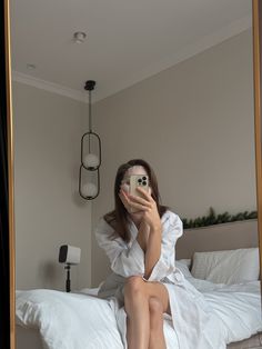 a woman sitting on top of a bed taking a selfie