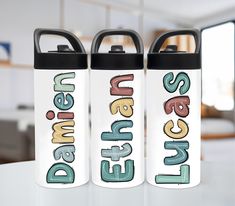 two personalized water bottles sitting on top of a white table next to each other