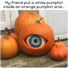 three pumpkins with an eye on them sitting in front of a door and two smaller pumpkins next to it