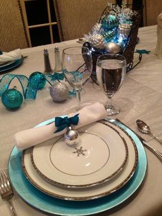 a table set for christmas with silver and blue decorations