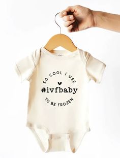 someone is holding up a baby's bodysuit