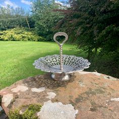 a metal dish sitting on top of a large rock