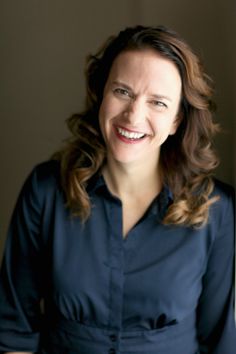 a woman smiling and wearing a blue shirt