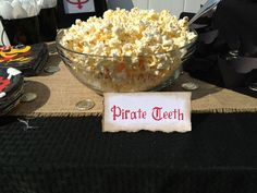 a bowl filled with popcorn sitting on top of a table next to other plates and napkins