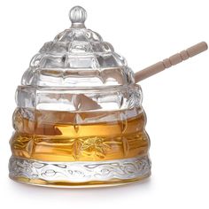 a glass honey pot with a wooden stick in it