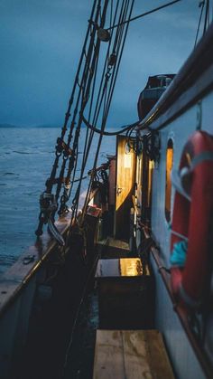 the back end of a boat in the ocean at night with its lights on and water behind it