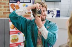 a man taking a photo with his camera in front of a woman at a fast food restaurant