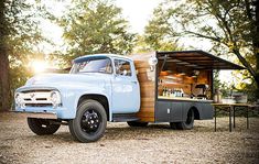 an old blue truck parked in the middle of a forest with a bar on it's back