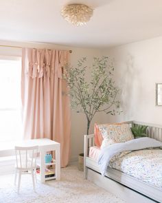 a bed room with a neatly made bed next to a window and a small table