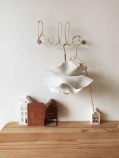 a wooden shelf topped with a white flower next to a book and toy house on top of it