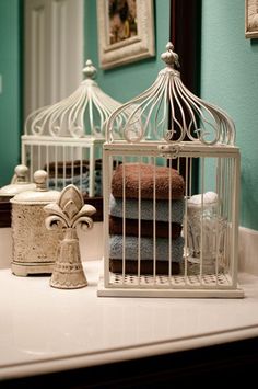 a white birdcage sitting on top of a bathroom counter next to a mirror