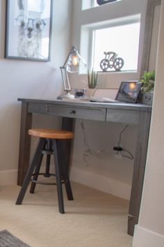 a room with a desk, chair and pictures hanging on the wall in front of it