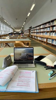 an open laptop computer sitting on top of a desk in a library filled with books