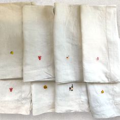 four white linen napkins with embroidered animals on them, all lined up in rows